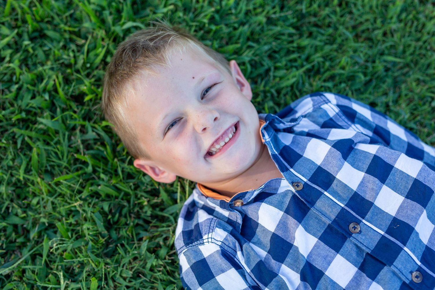 young boy laying in grass smiling family photo shoot photography by ashley chance delmar delaware otter creek acres