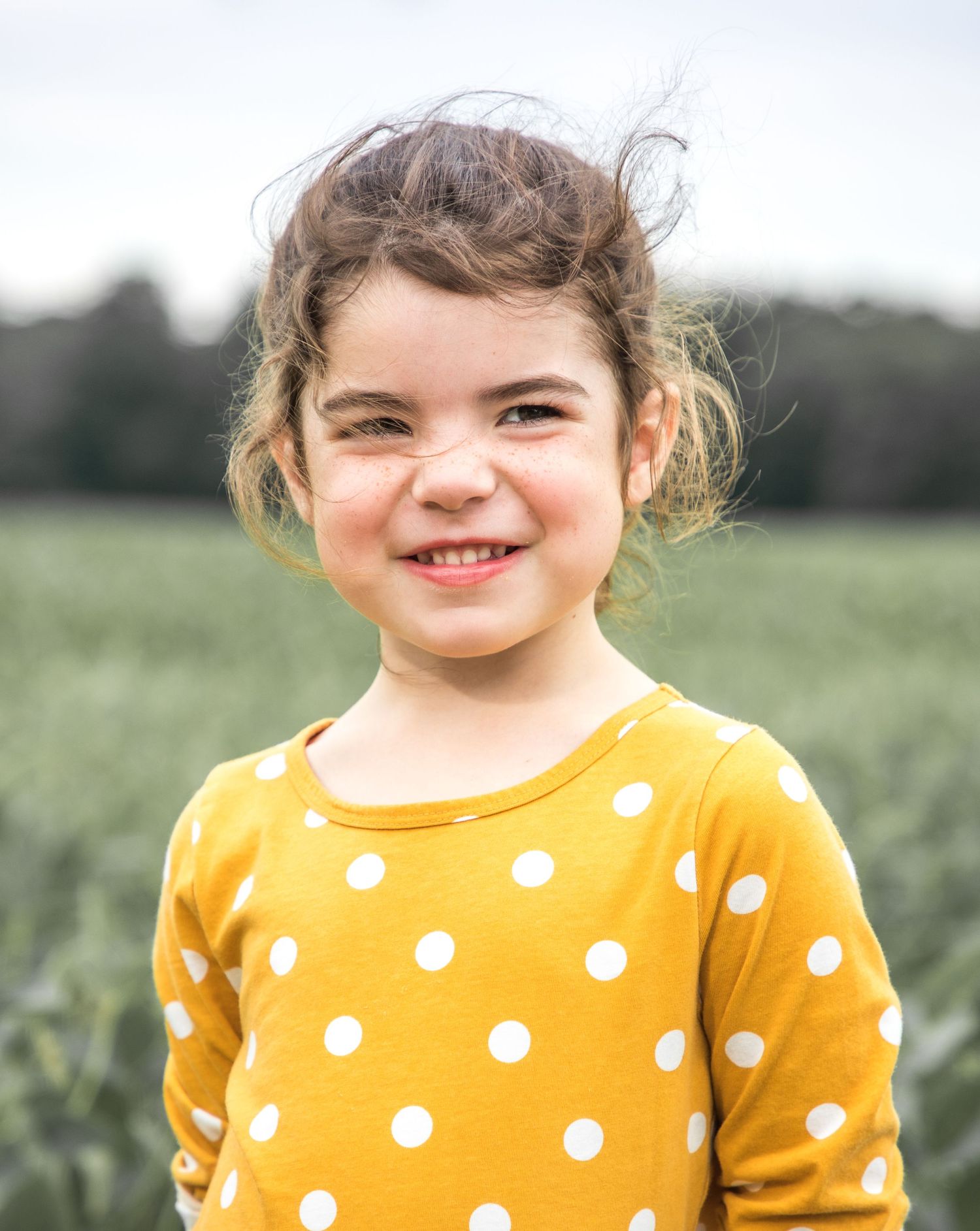 a young girl with a field of soybeans behind her wearing an old navy dress photography by ashley chance