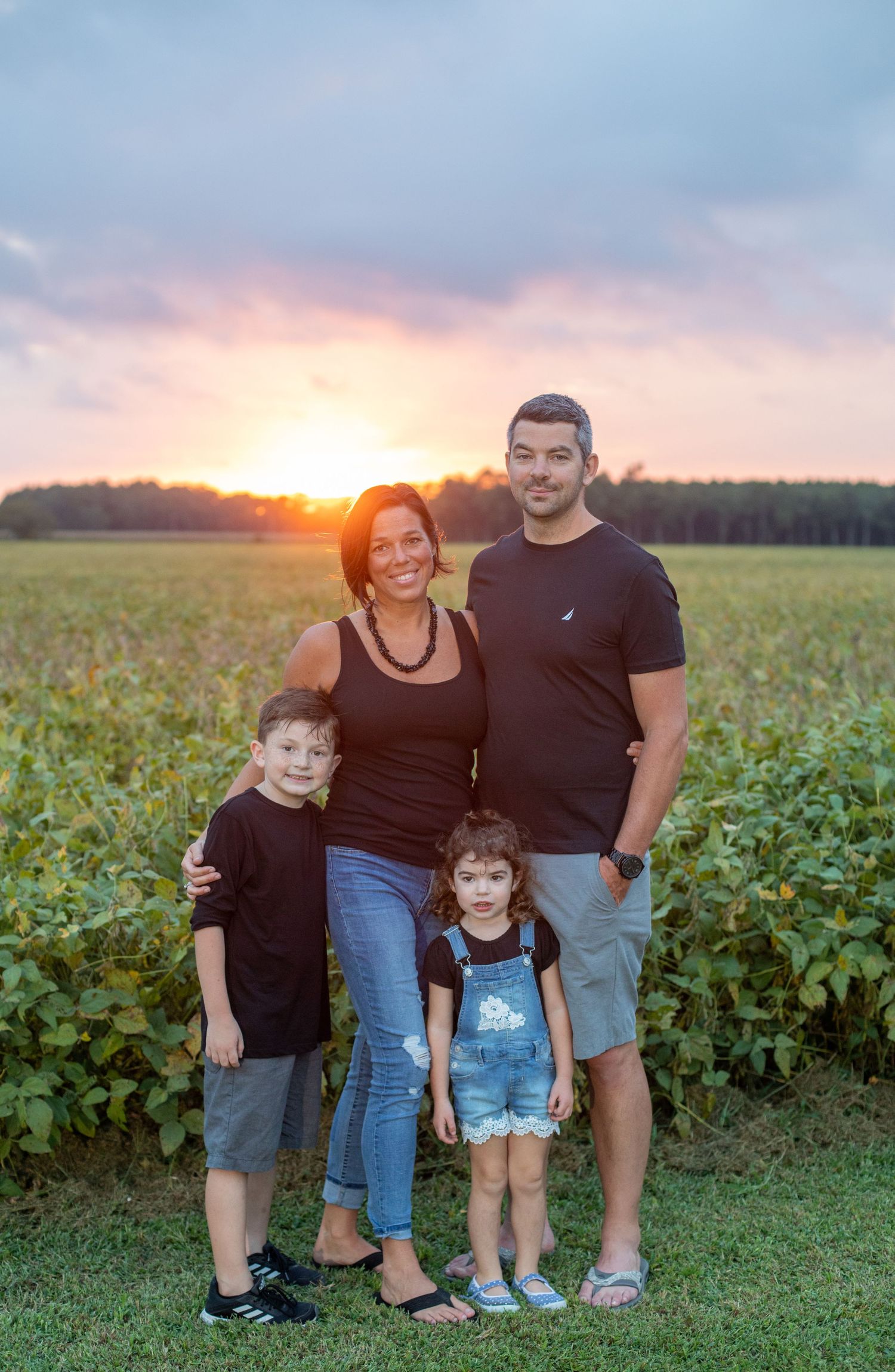 family photo session mom dad son and daughter with a sunset behind them soybean fields shot with a canon camera and mag mod system