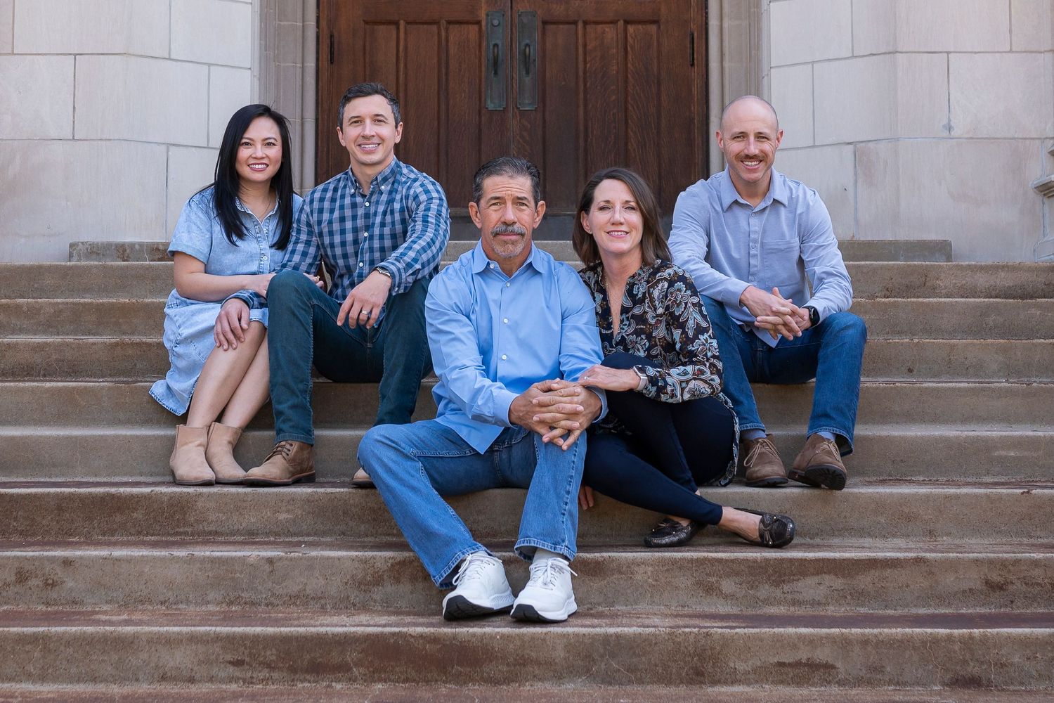 Family group portrait sitting on stone steps of a building entrance.