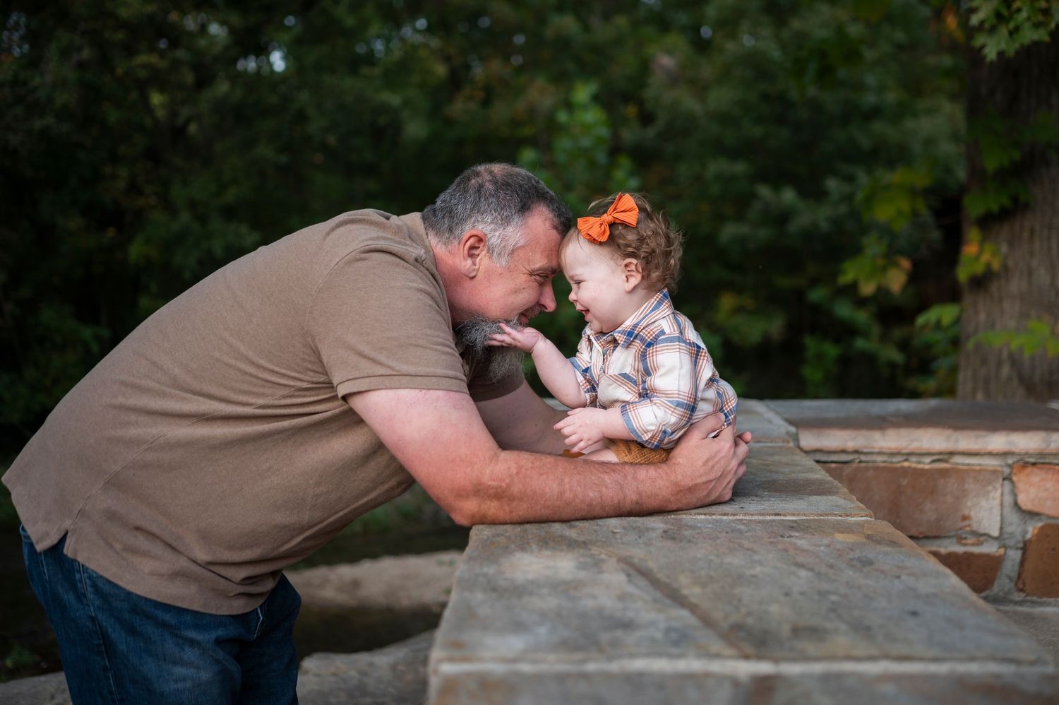 A tender moment shared between parent and child leaning over a wooden surface outdoors.