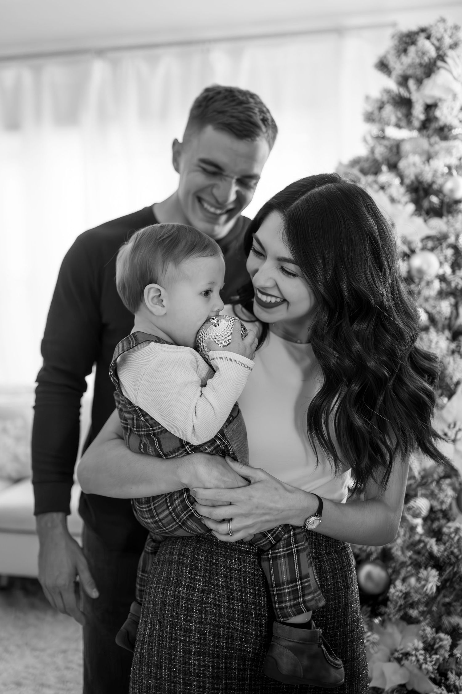 A happy family moment captured in black and white as they laugh together near their Christmas tree.