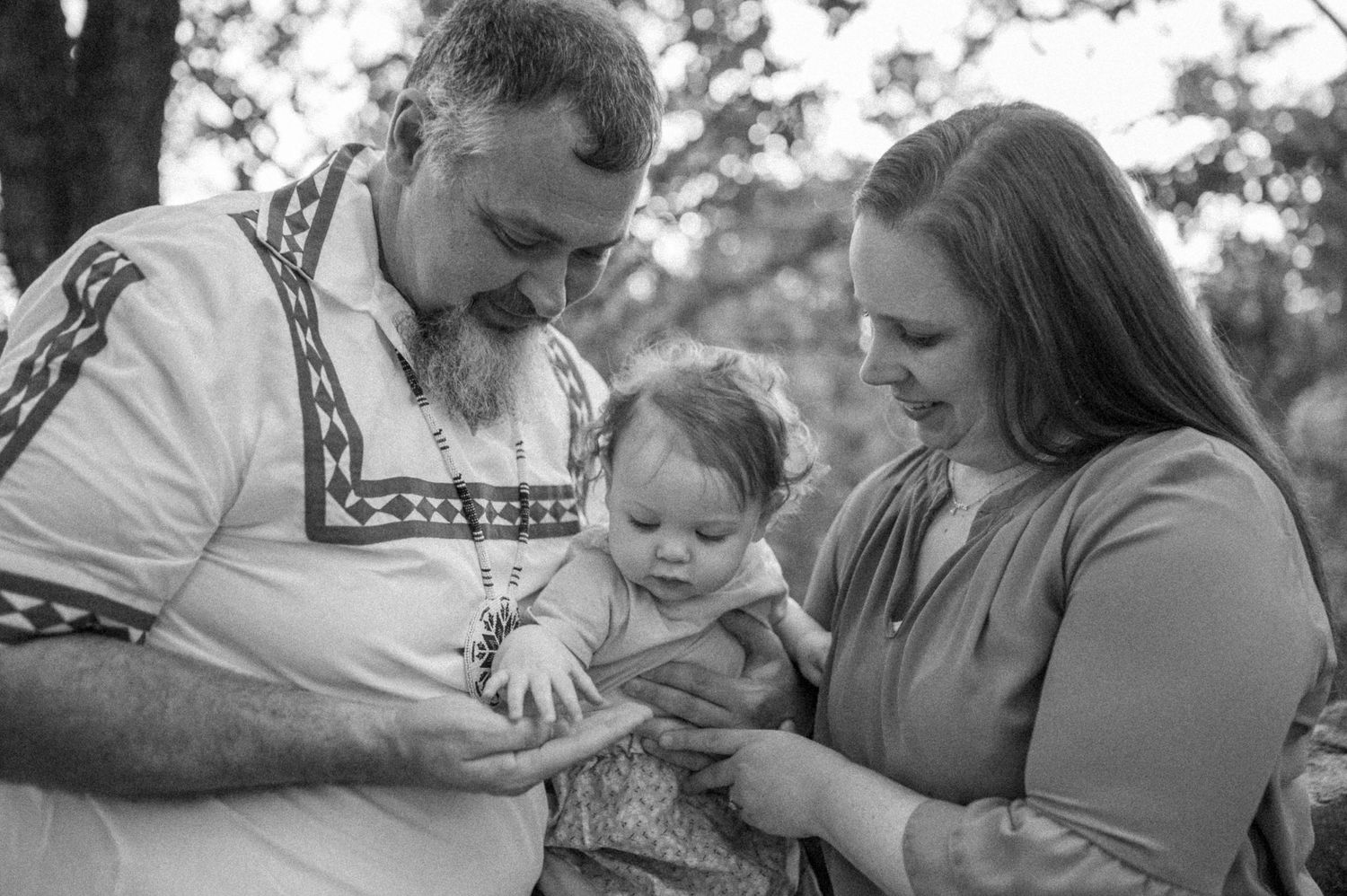 Black and white family portrait showing tender moment outdoors.