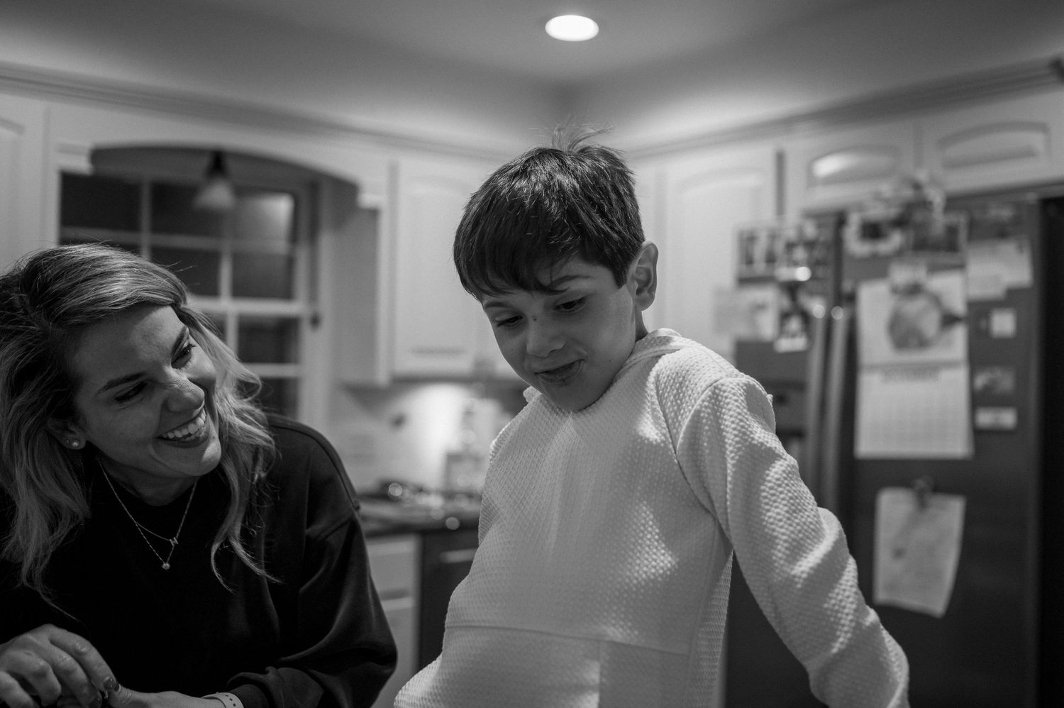 A heartwarming black and white moment of interaction in a home kitchen.