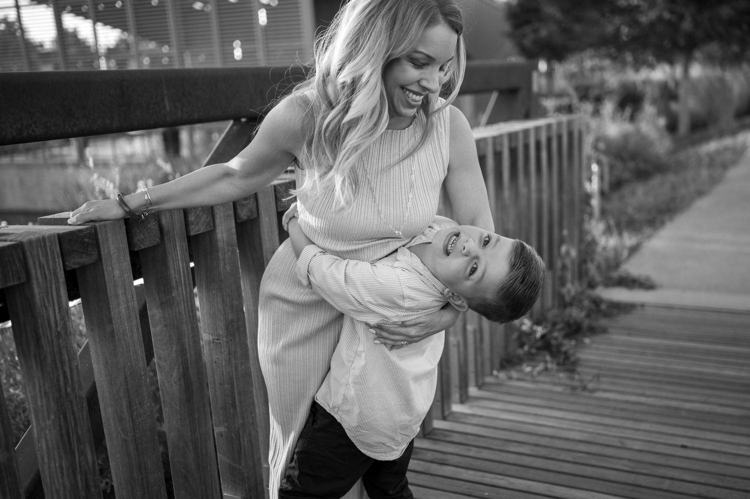 A sweet candid black and white moment captured on a wooden deck in an outdoor setting.