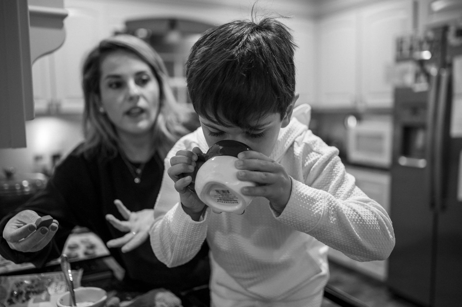 A candid black and white kitchen scene showing someone enjoying a snack.