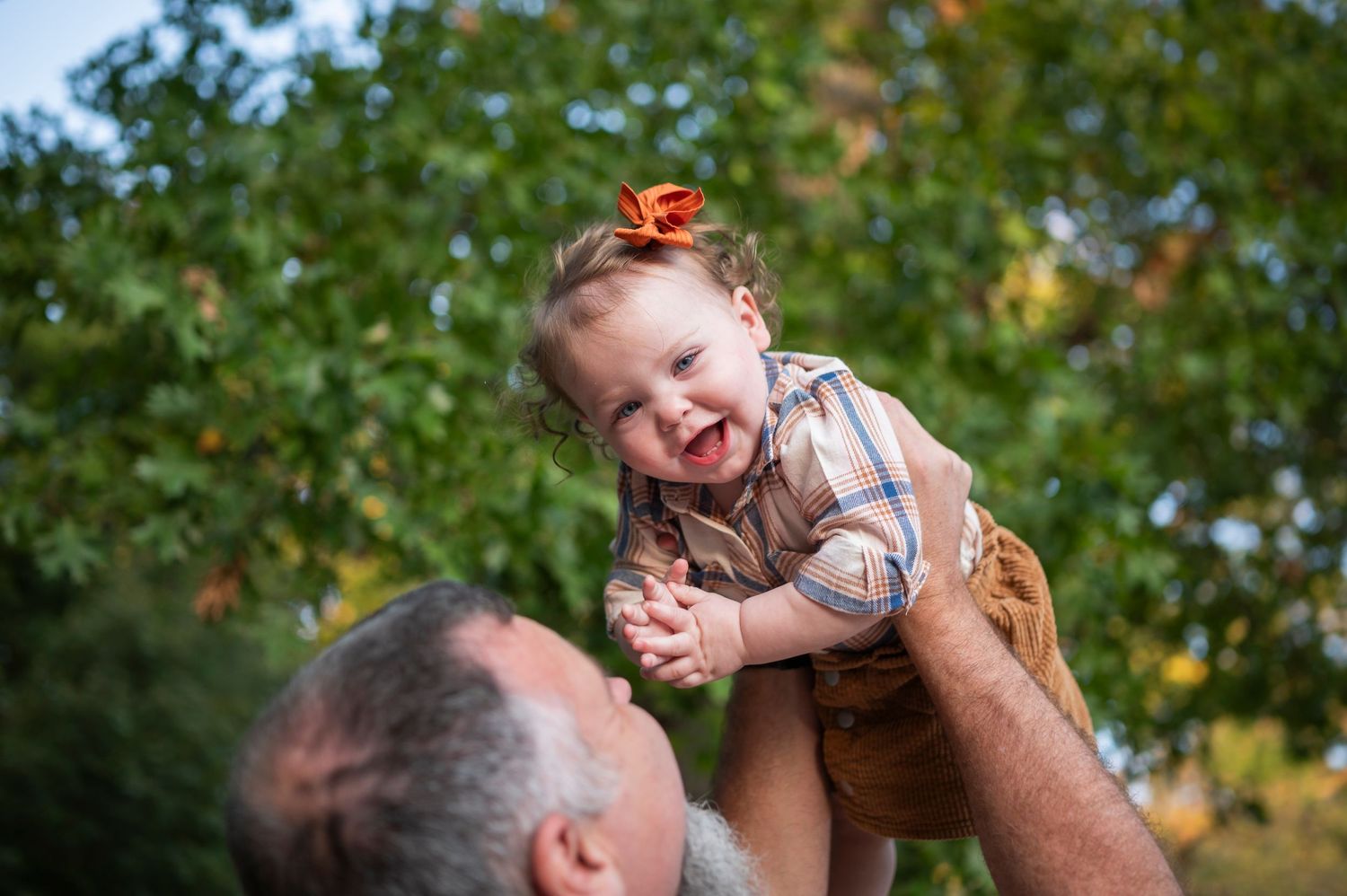 Joyful outdoor moment captured during playtime against autumn foliage background.