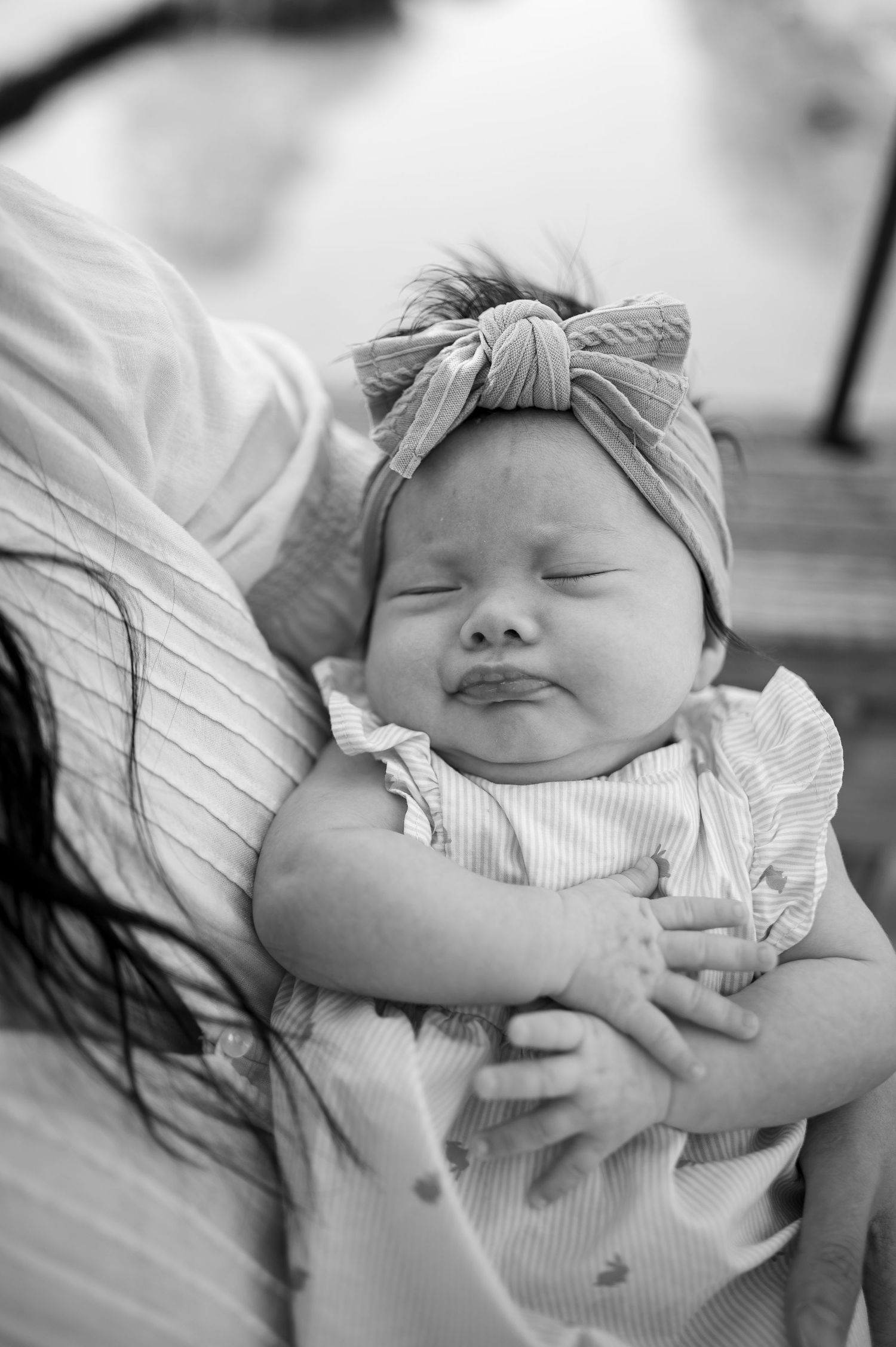A sleeping newborn baby in white clothing captured in black and white photography.