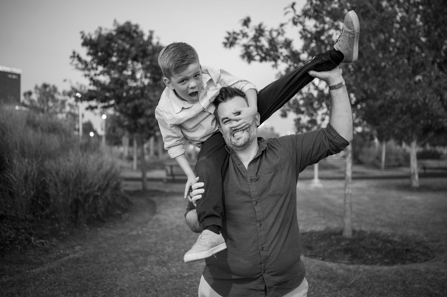 Black and white candid photo showing joyful playtime in an outdoor park setting.