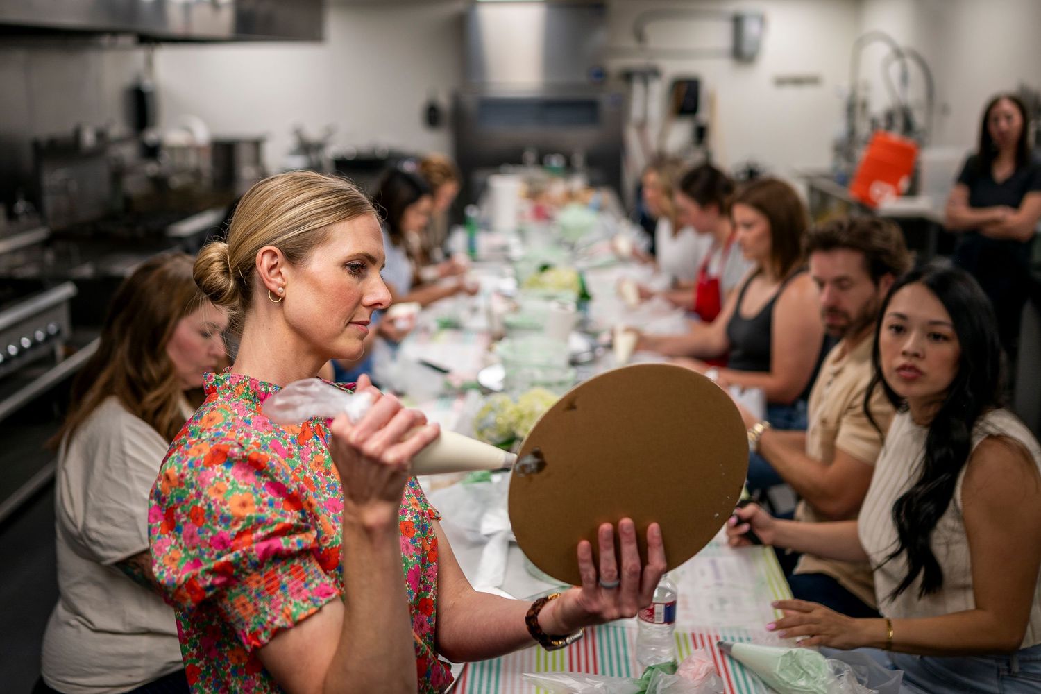 A group of people gather around a table enjoying food and drinks at a social dining event.