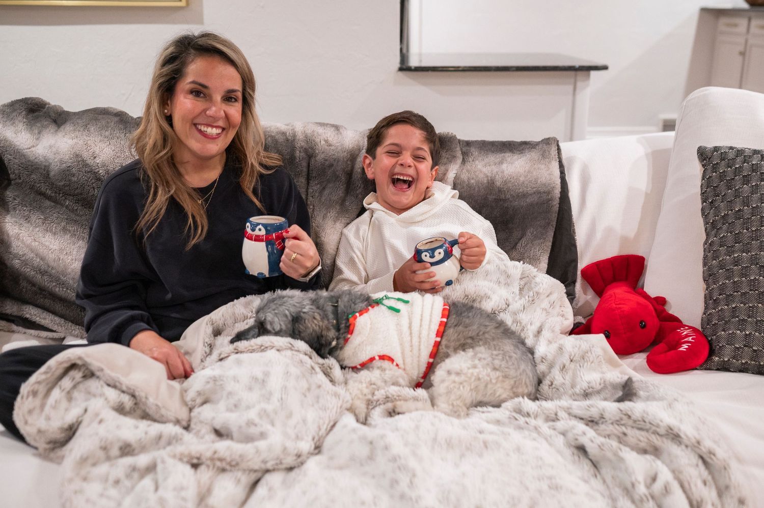 A happy moment of two people enjoying snacks together on a comfortable gray couch.