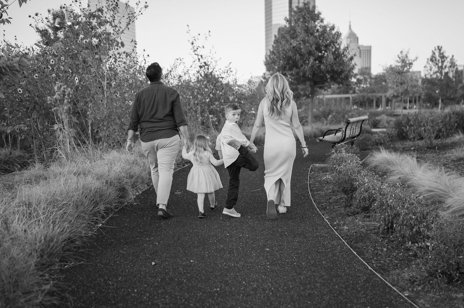 Black and white image of a family walking together on a garden path at sunset.