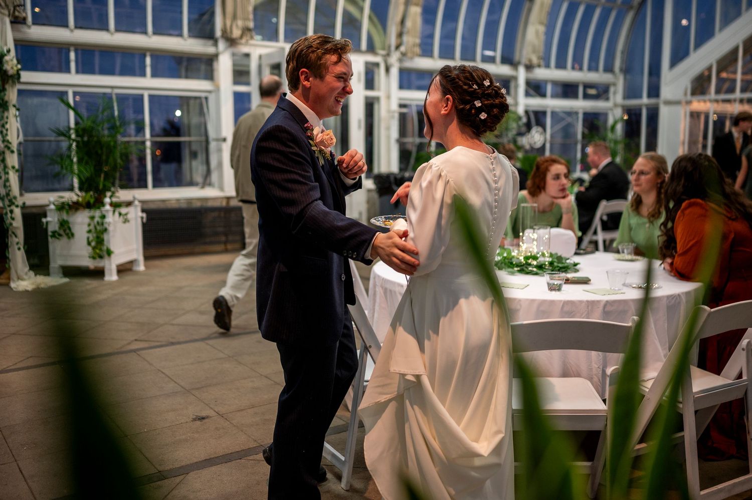 Couple sharing their first dance at an elegant greenhouse wedding reception.