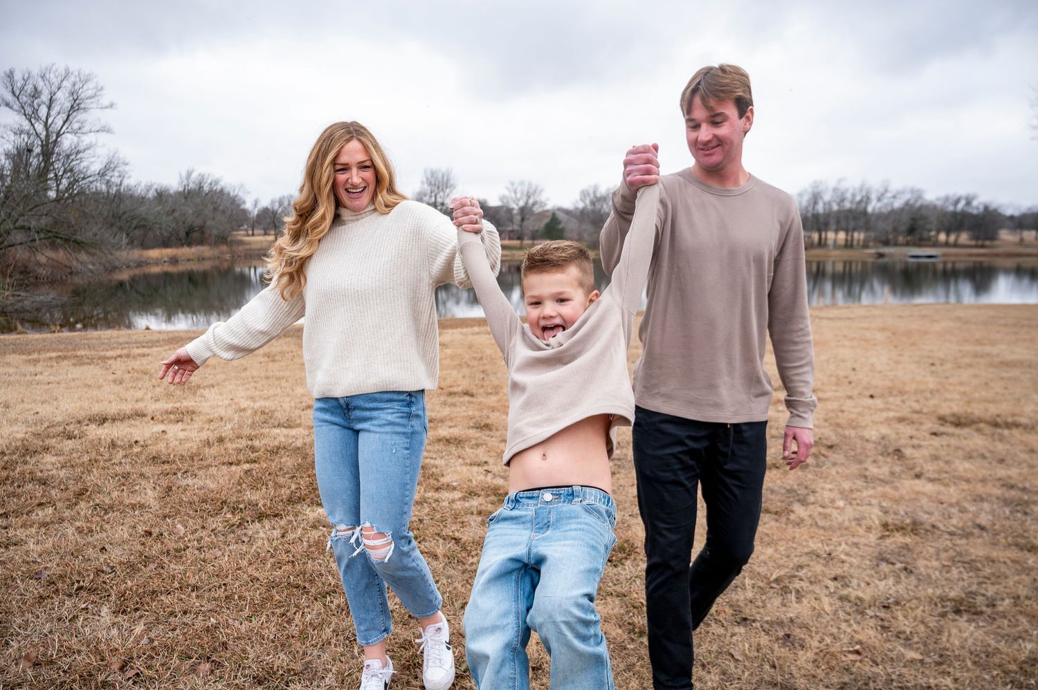 A joyful family moment captured outdoors by a lake on a winter day.