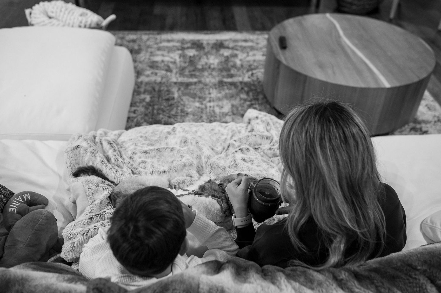 A relaxing scene of people laying on a couch watching television together.
