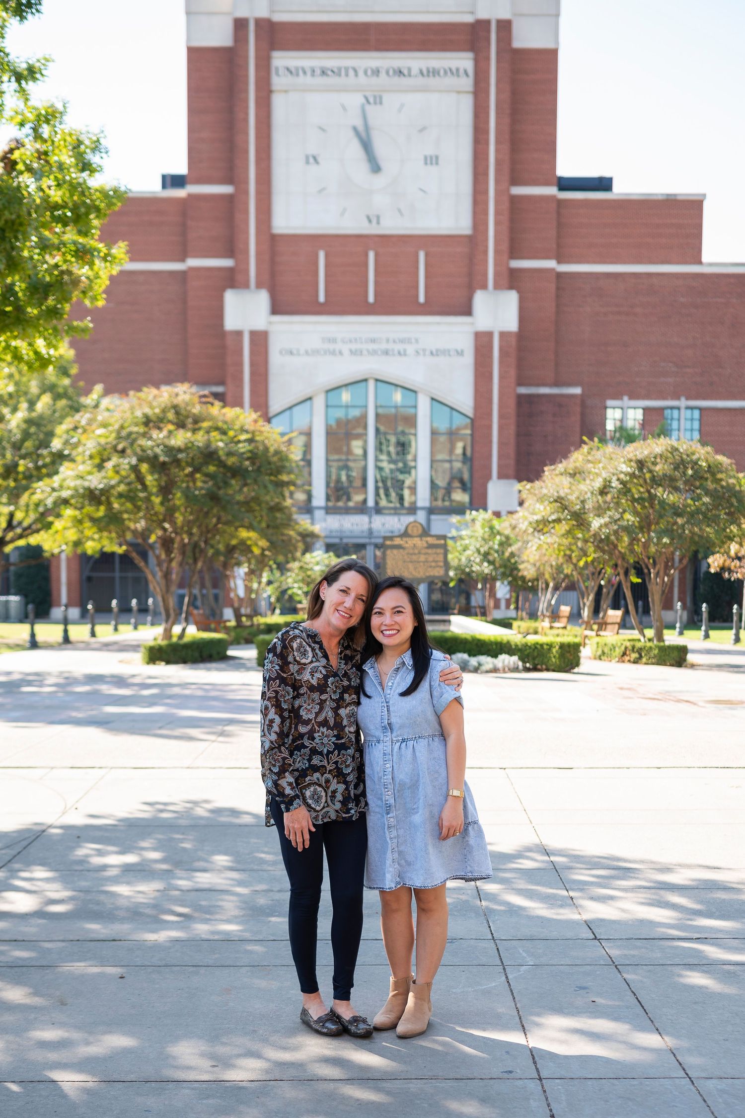 Two people standing in front of a large university building with a prominent clock tower.