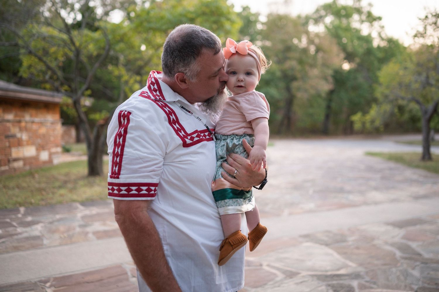 Parent holding small child wearing pink outfit during outdoor photo session.