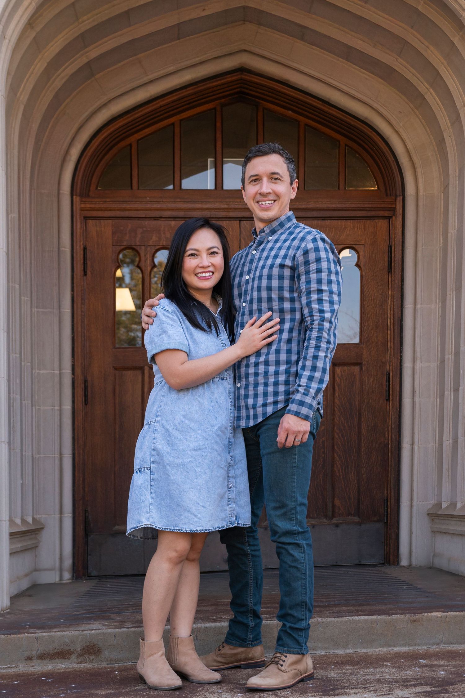 A couple stands together in an arched doorway of a stone building.