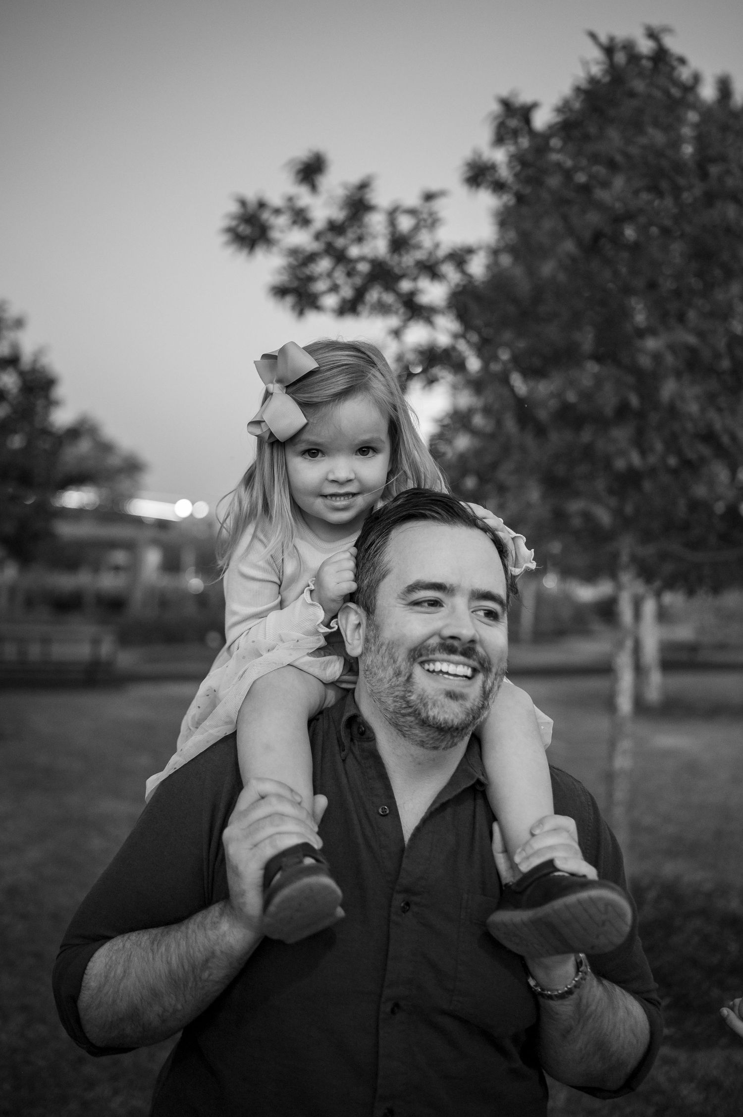 Black and white photo of piggyback ride outdoors with trees in background.
