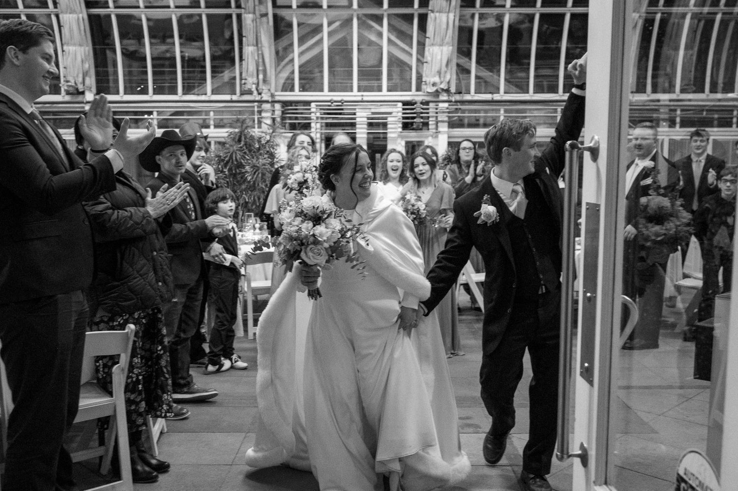 A joyful wedding ceremony moment captured in black and white with guests celebrating a newly married couple.