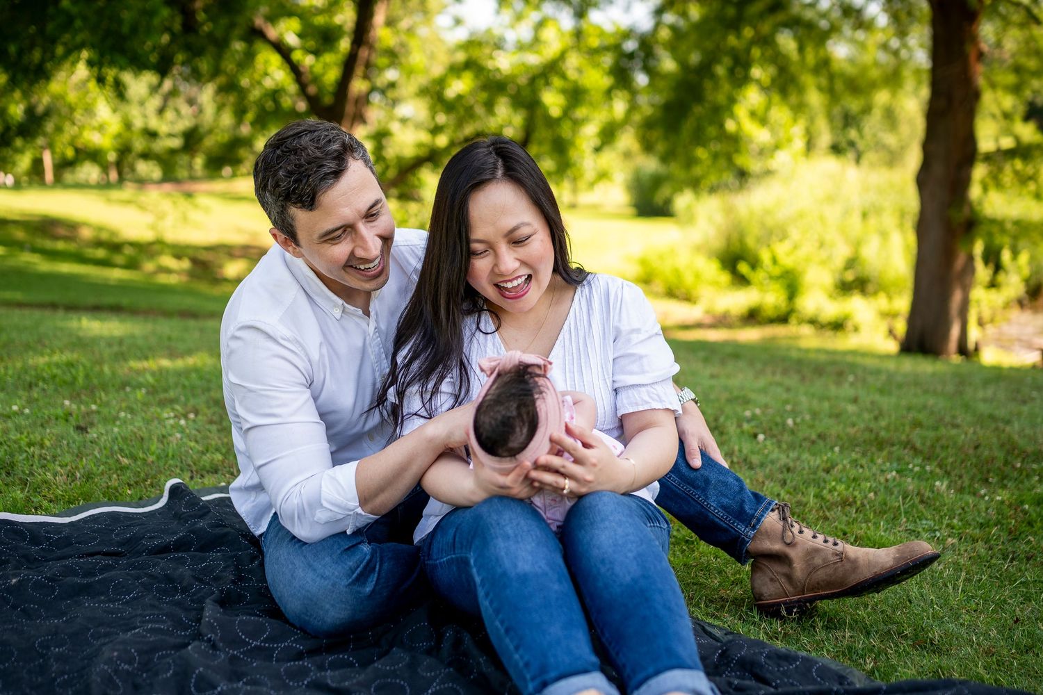 A couple relaxes together on lush green grass in a scenic park during a warm sunny afternoon.