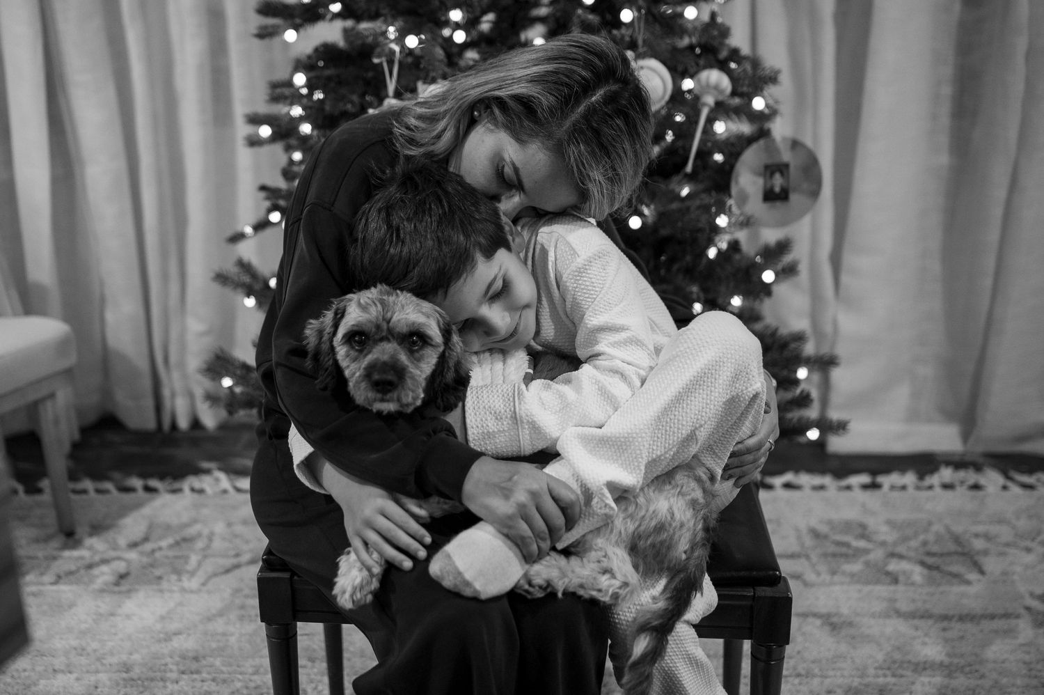 A cozy family moment with a dog in front of a Christmas tree.