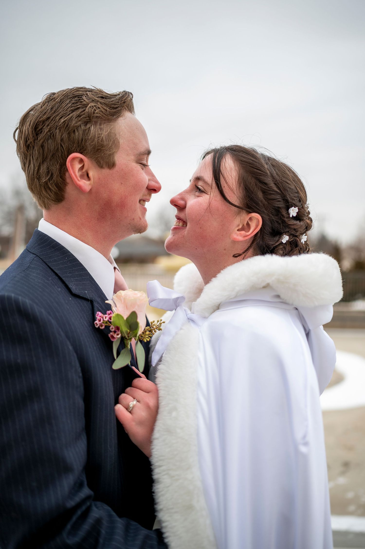 A romantic winter wedding moment showing a couple gazing at each other with joy while wearing formal attire.