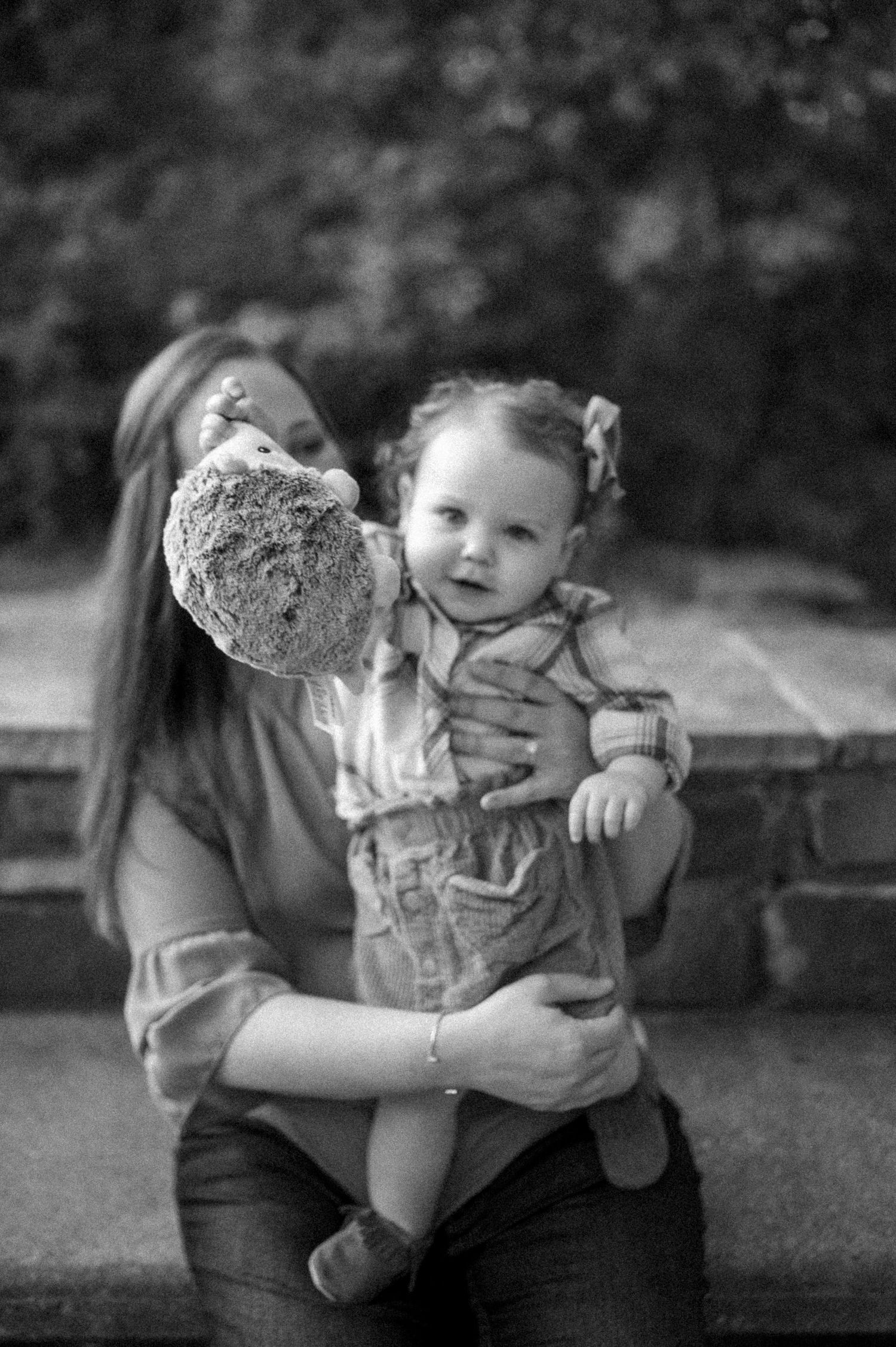 Black and white portrait showing tender family moment on stone steps outdoors.