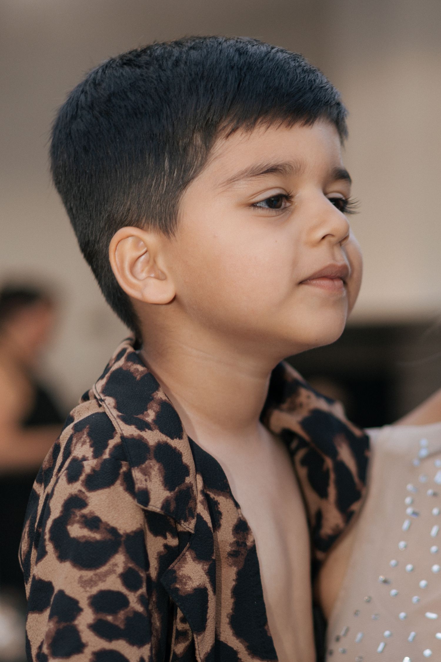 Young child wearing a leopard print shirt smiling and posing in a series of playful expressions.