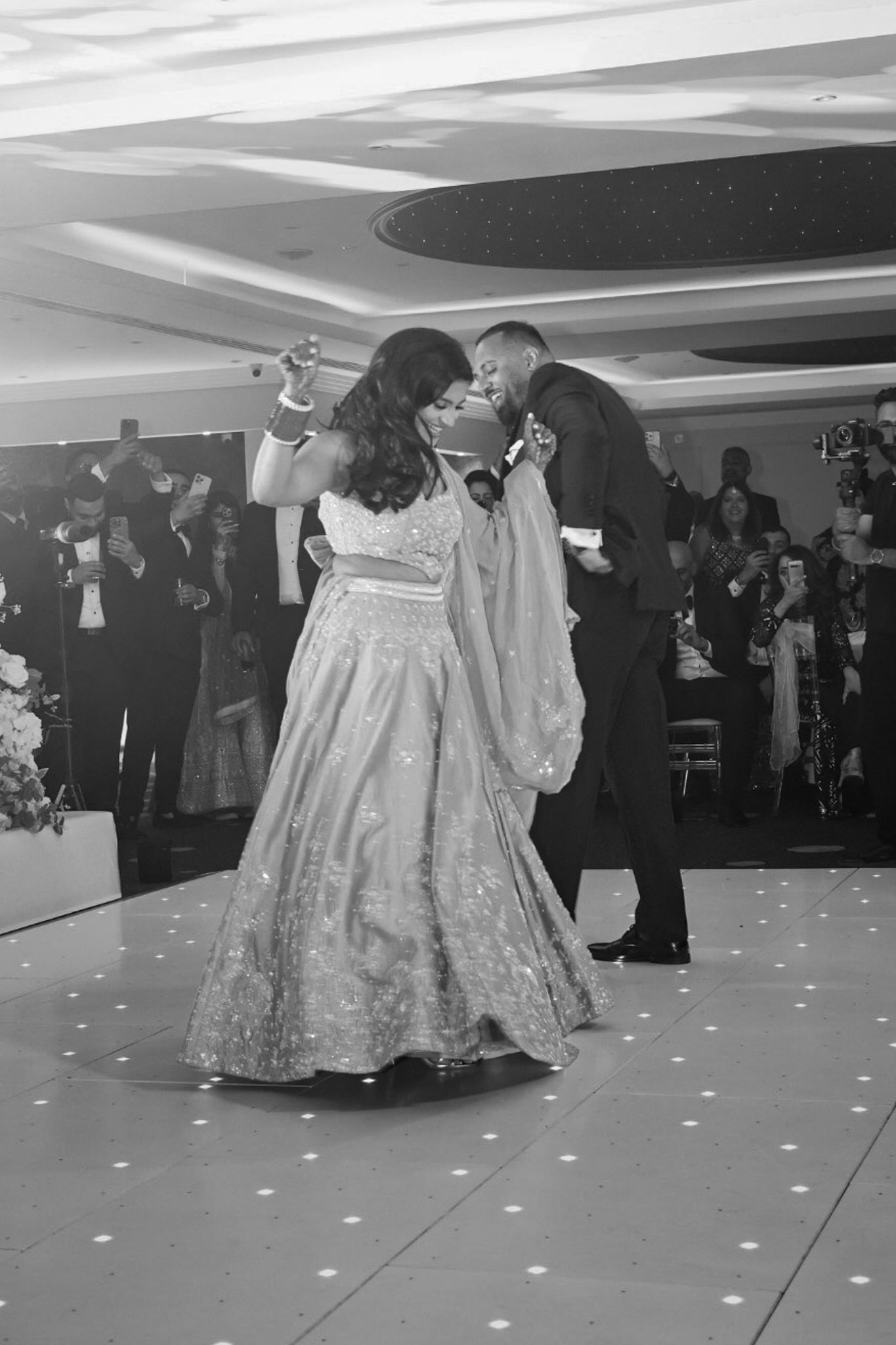 Wedding reception dance floor with couples dancing under decorative lighting.