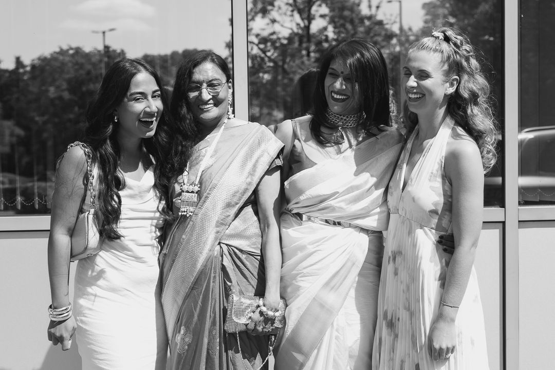 Group of bridesmaids in white dresses laughing together outdoors.