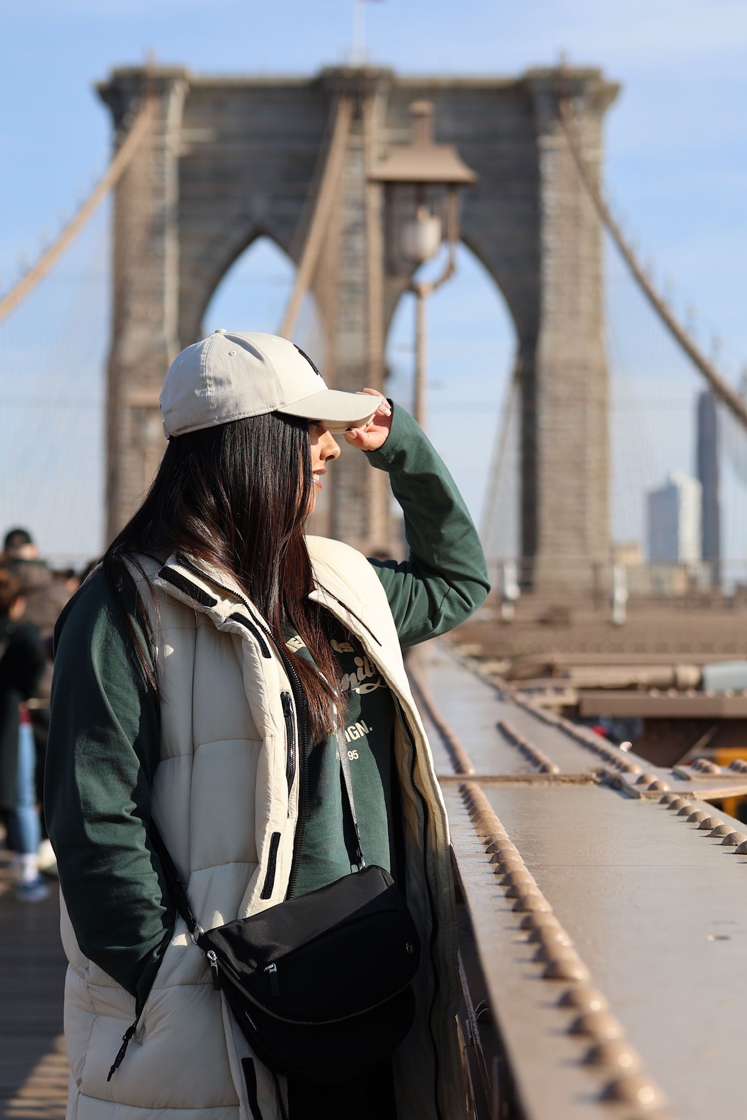 Tourist enjoying view from Brooklyn Bridge on sunny day.