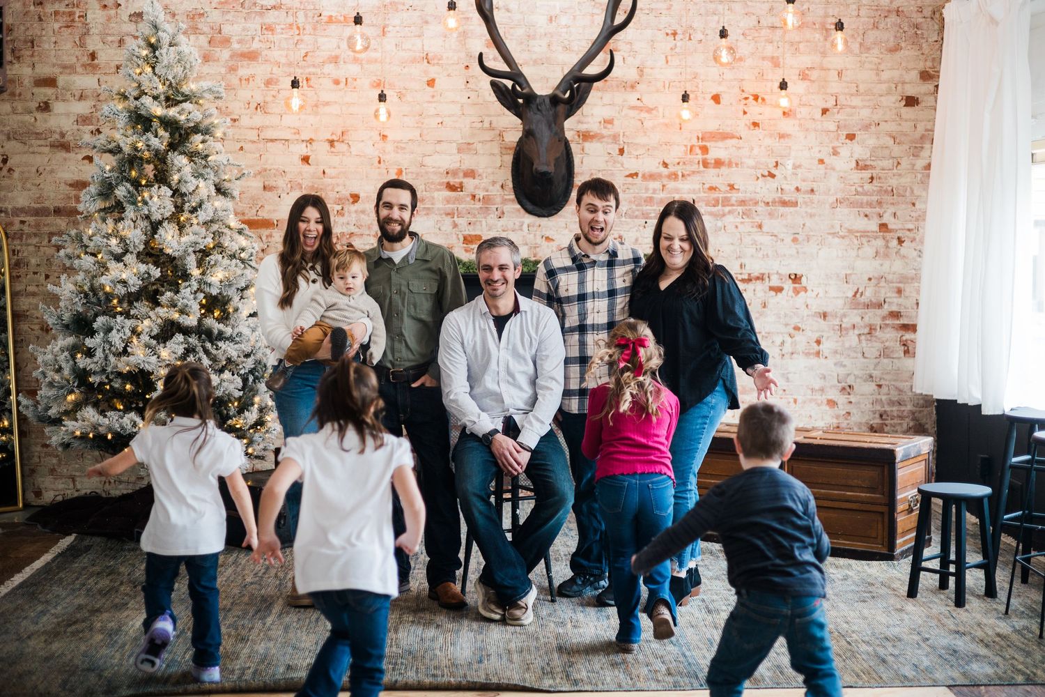 A multigenerational family gathers and laughs together in a festively decorated room with a Christmas tree.
