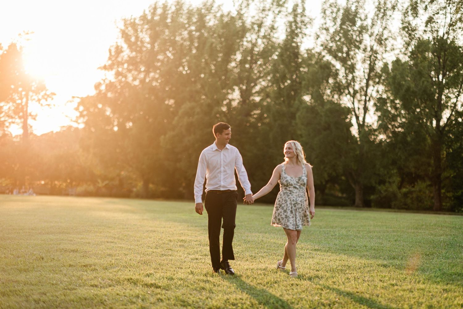 Couple holding hands walking through Ault park at golden hour.