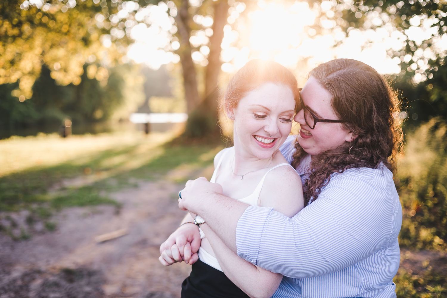 Joyful couple embracing and laughing together in warm golden sunlight outdoors.