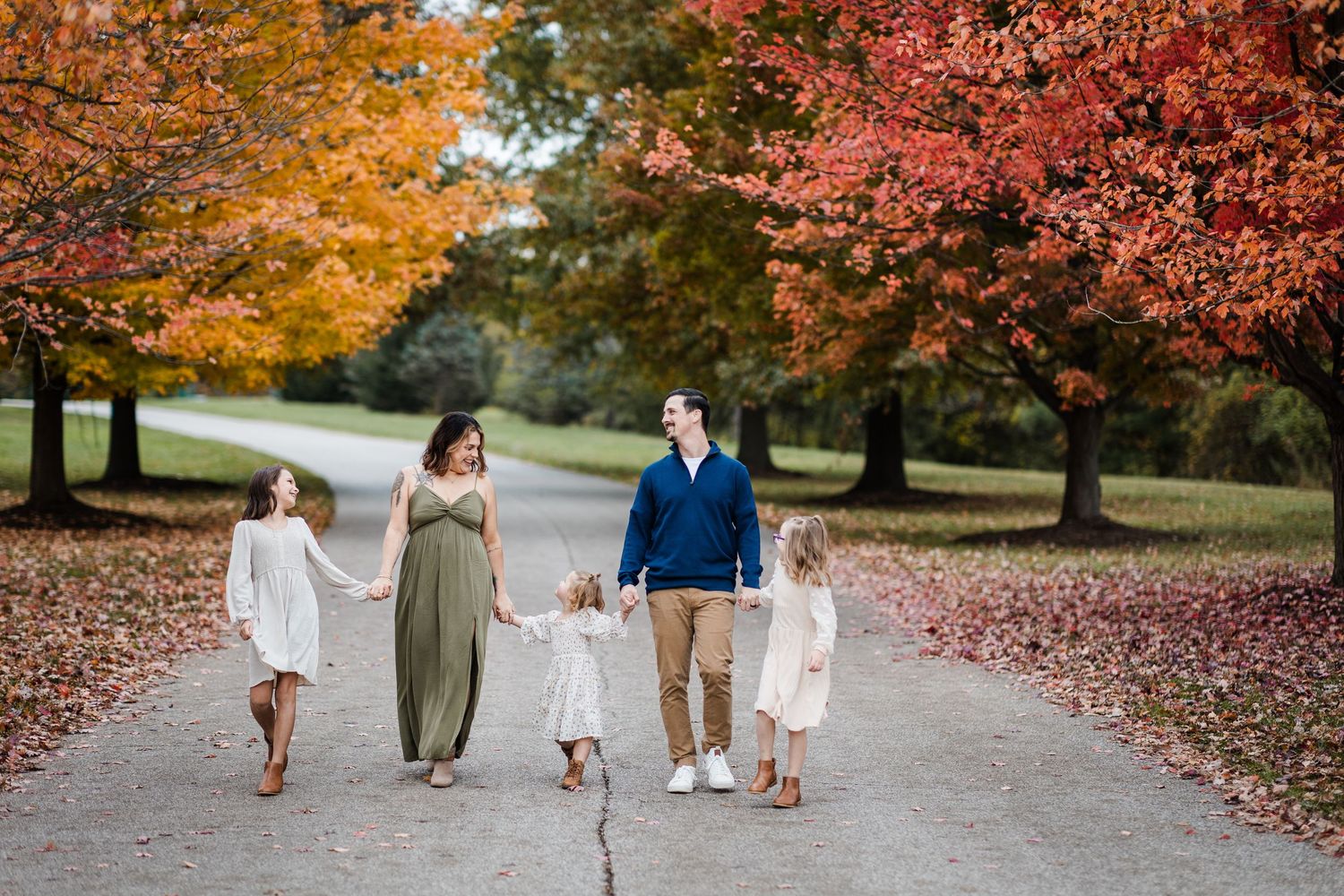 Mother and father walking with three daughters on fall tree-lined path at French Park.