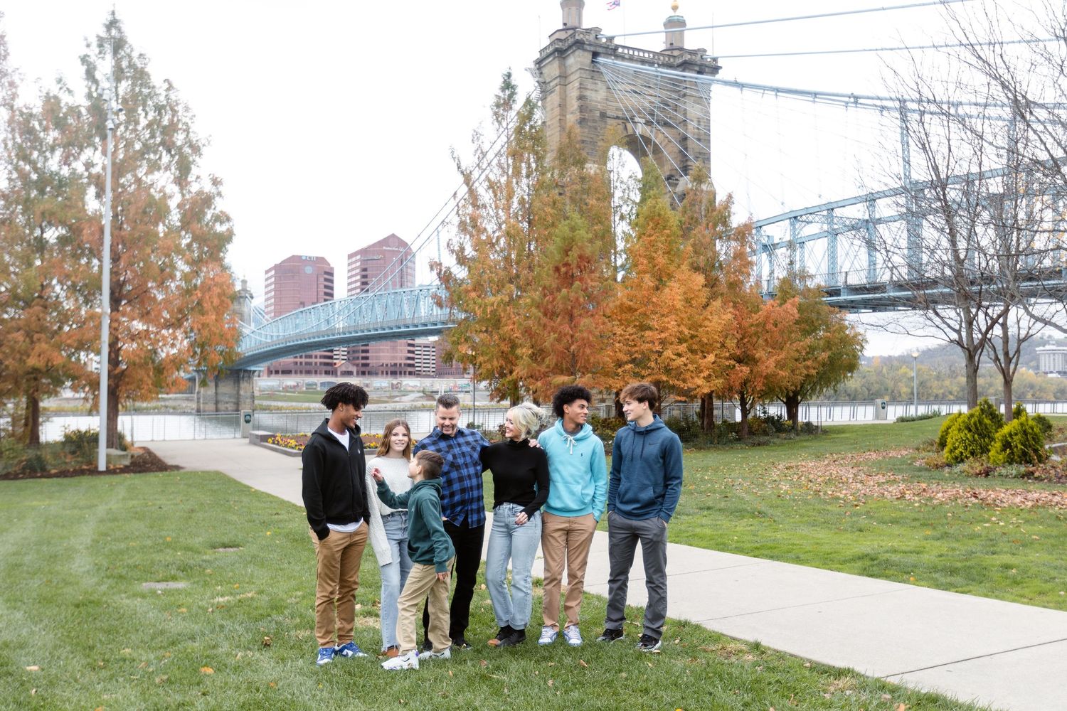 A family standing together on a riverside path with the roebling bridge behind them.