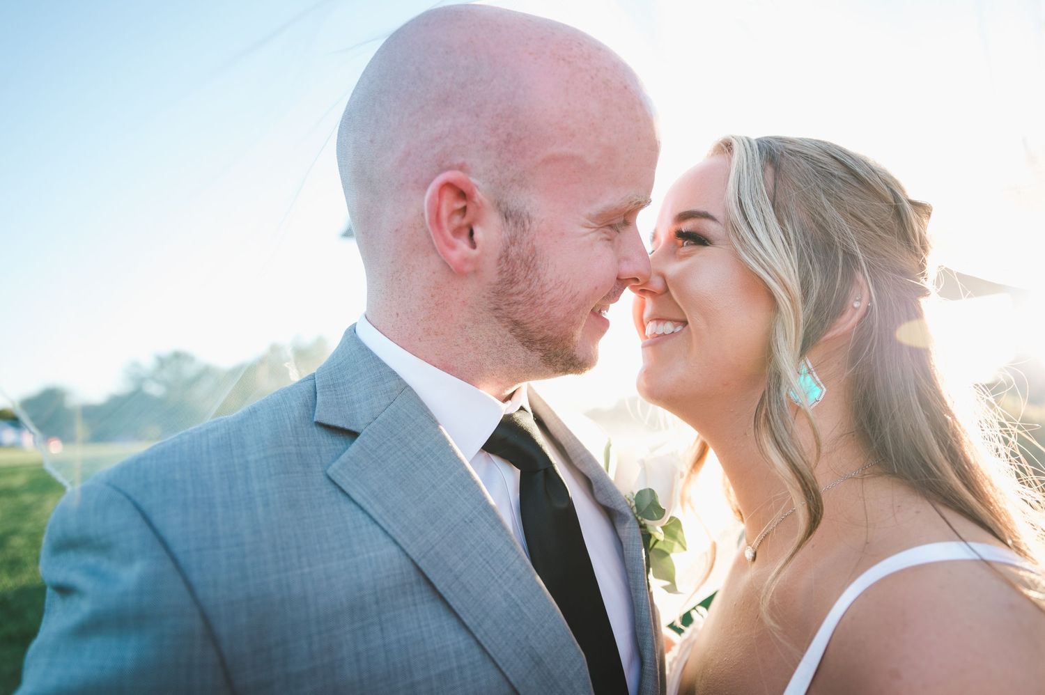 Bride and groom sharing romantic moment outdoors in golden sunlight on wedding day.