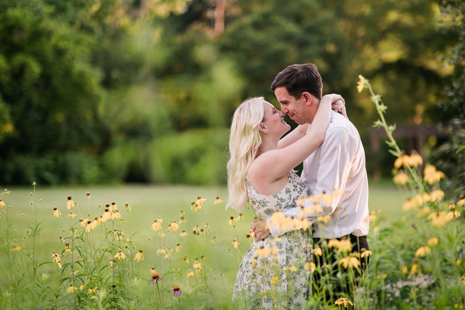 Couple sharing a romantic kiss surrounded by vibrant yellow wildflowers in a lush green meadow.