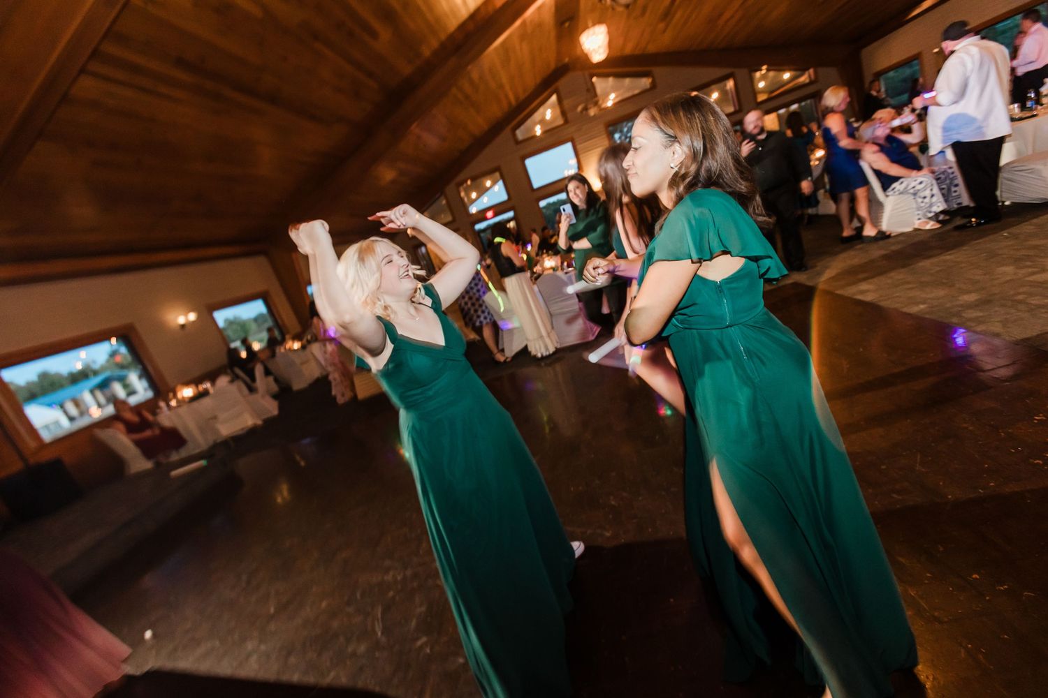 Bridesmaids in emerald green gowns dance joyfully together at wedding reception at Lake Lyndsay.