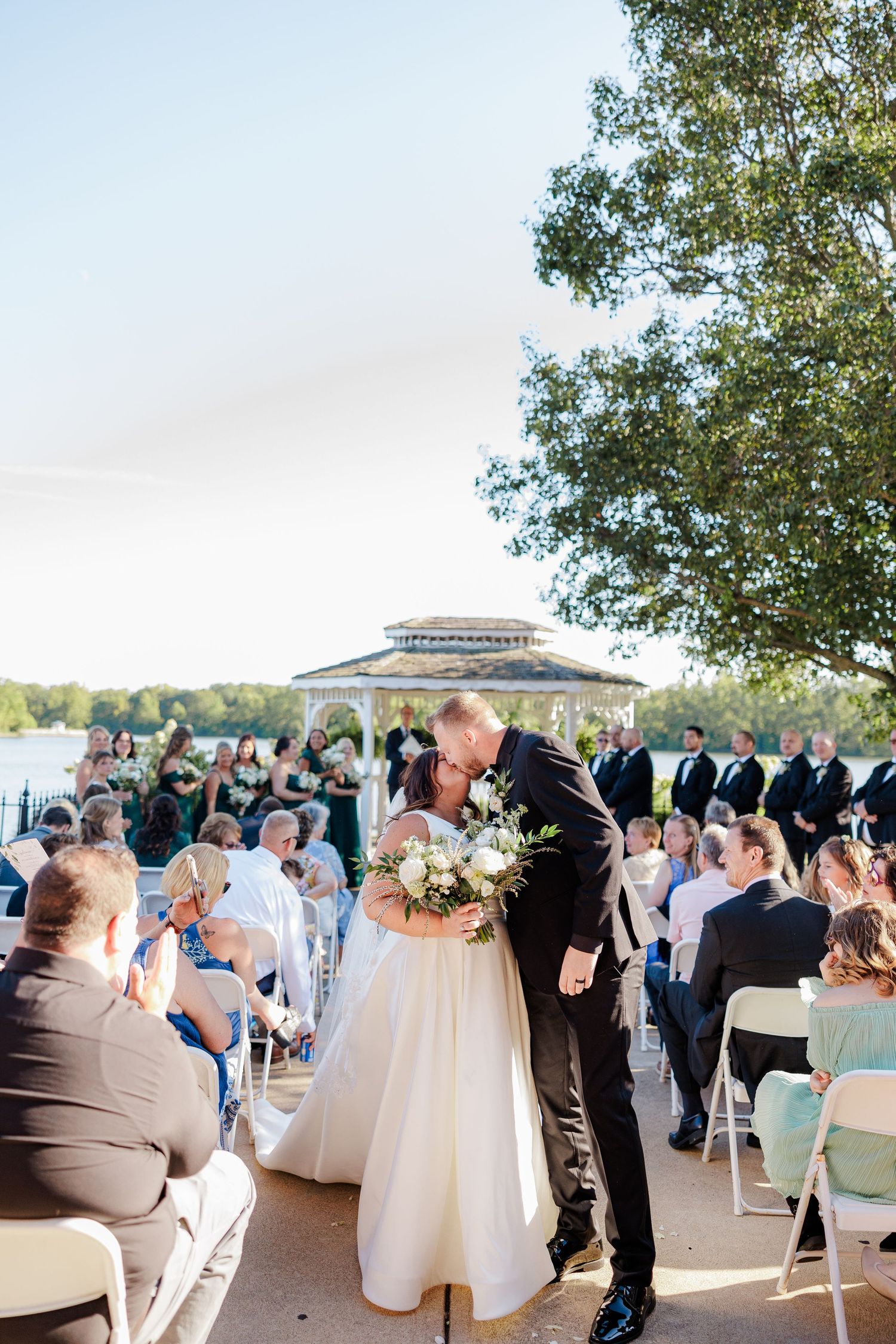 Bride and groom share a first kiss at a Lake Lyndsay ceremony with gazebo backdrop.