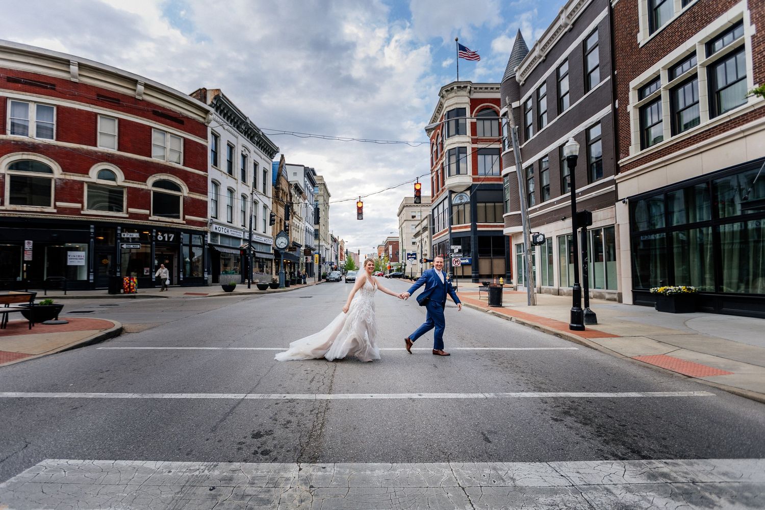 Bride and groom cross a downtown street intersection in a charming historic city setting.