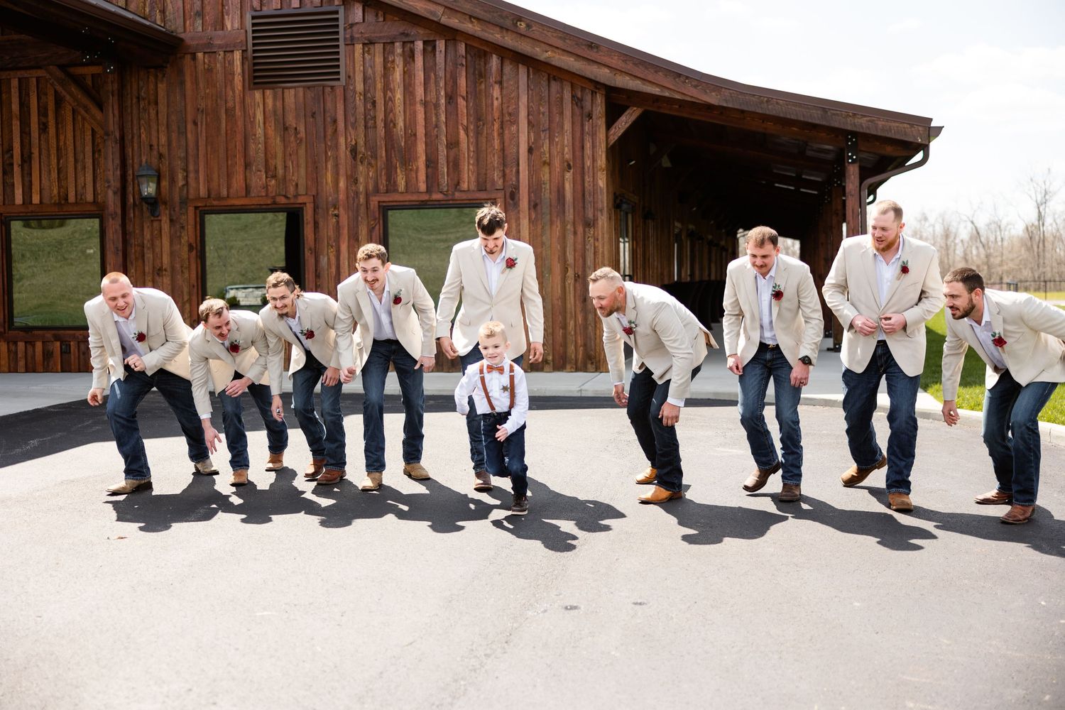 Groomsmen in tan blazers and jeans pose playfully outside Hanover Reserve.
