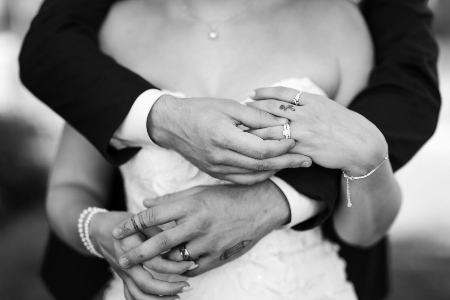 Close-up black and white photo of bride and groom showing off their wedding rings.