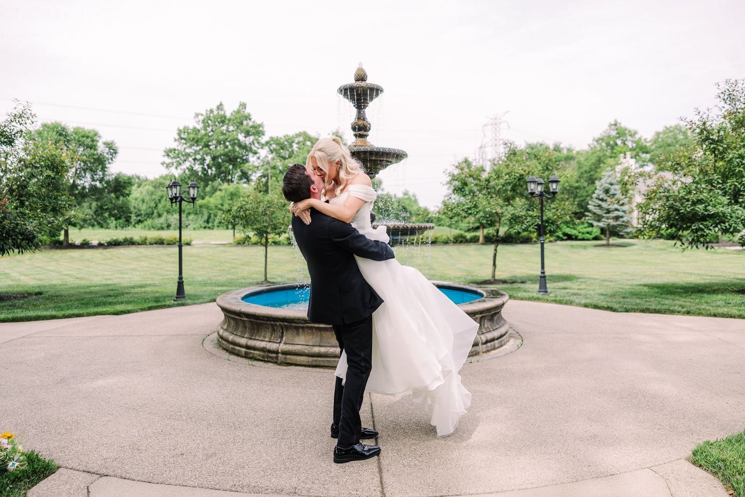 Groom lifting bride in a romantic dip near a decorative fountain at The Manor House.
