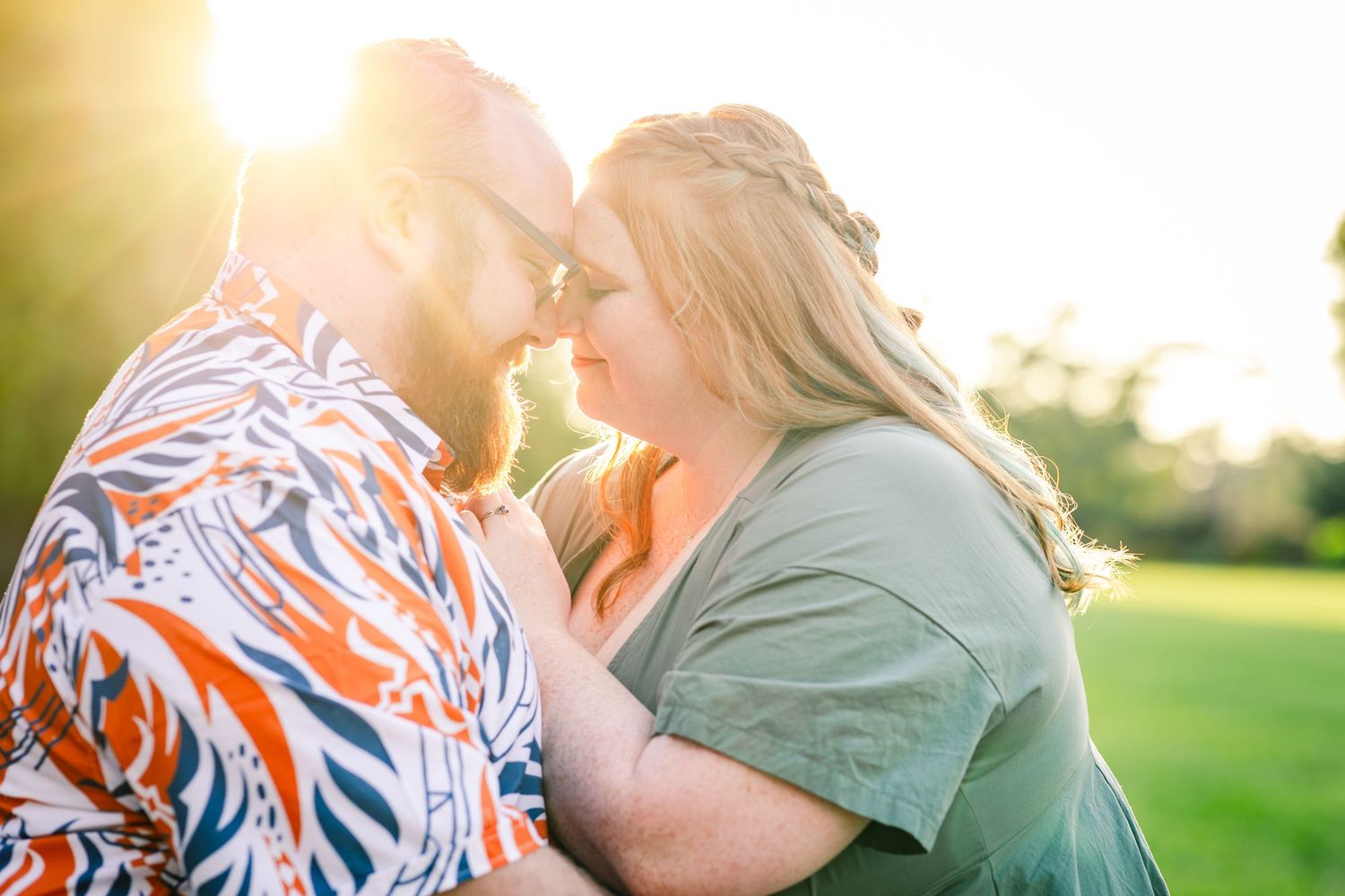 Couple sharing a romantic almost-kiss bathed in golden sunset light outdoors.