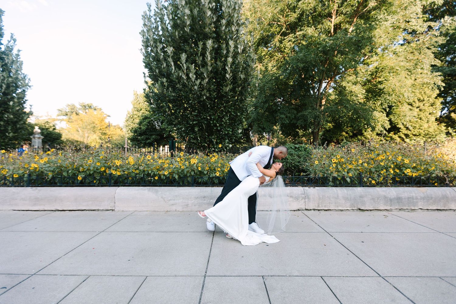 Groom dipping his bride outdoors near a colorful garden at Washington Park in Cincinnati.