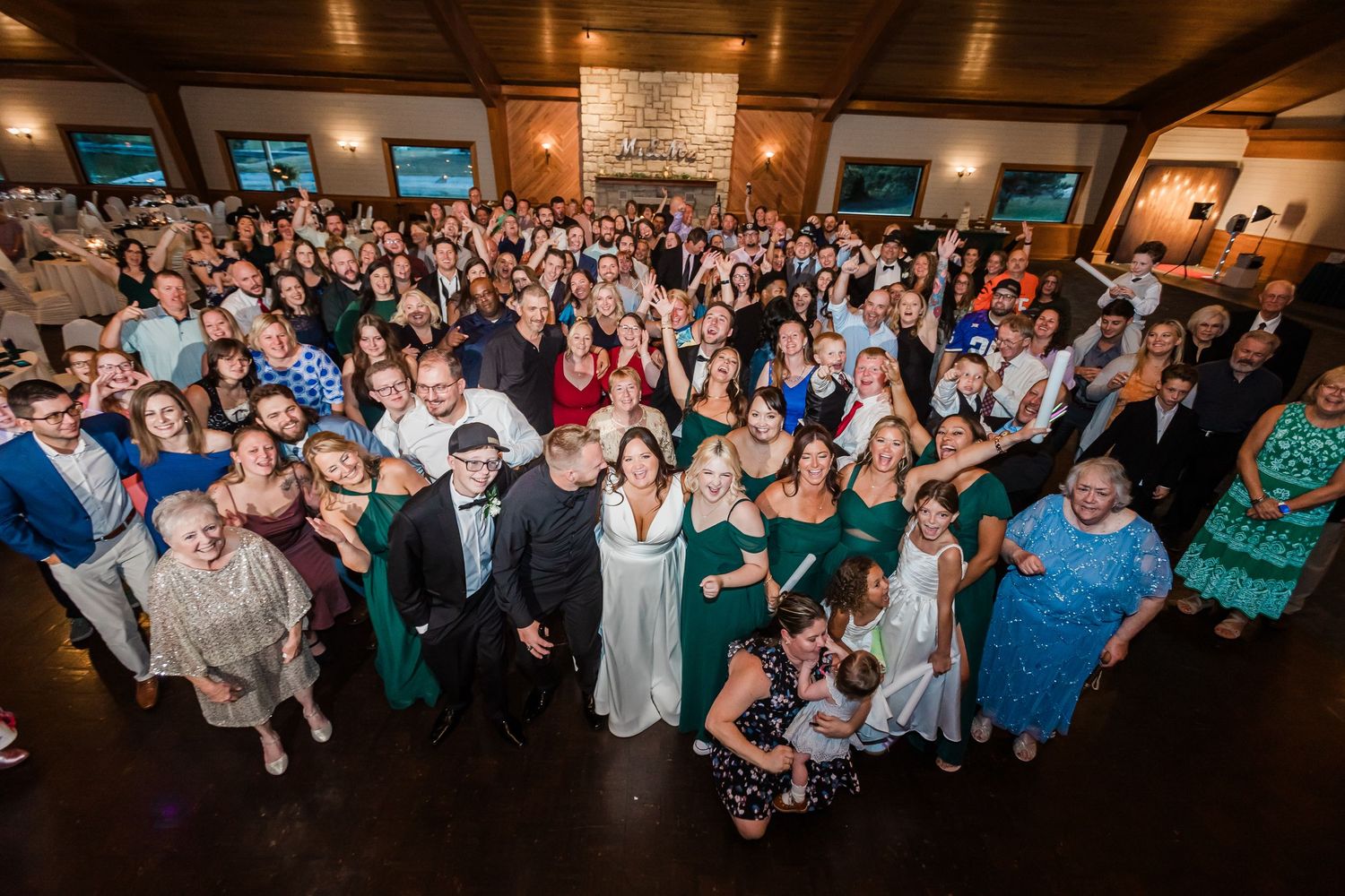 Large wedding reception group photo with all guests gathered inside a rustic venue at Lake Lyndsay.