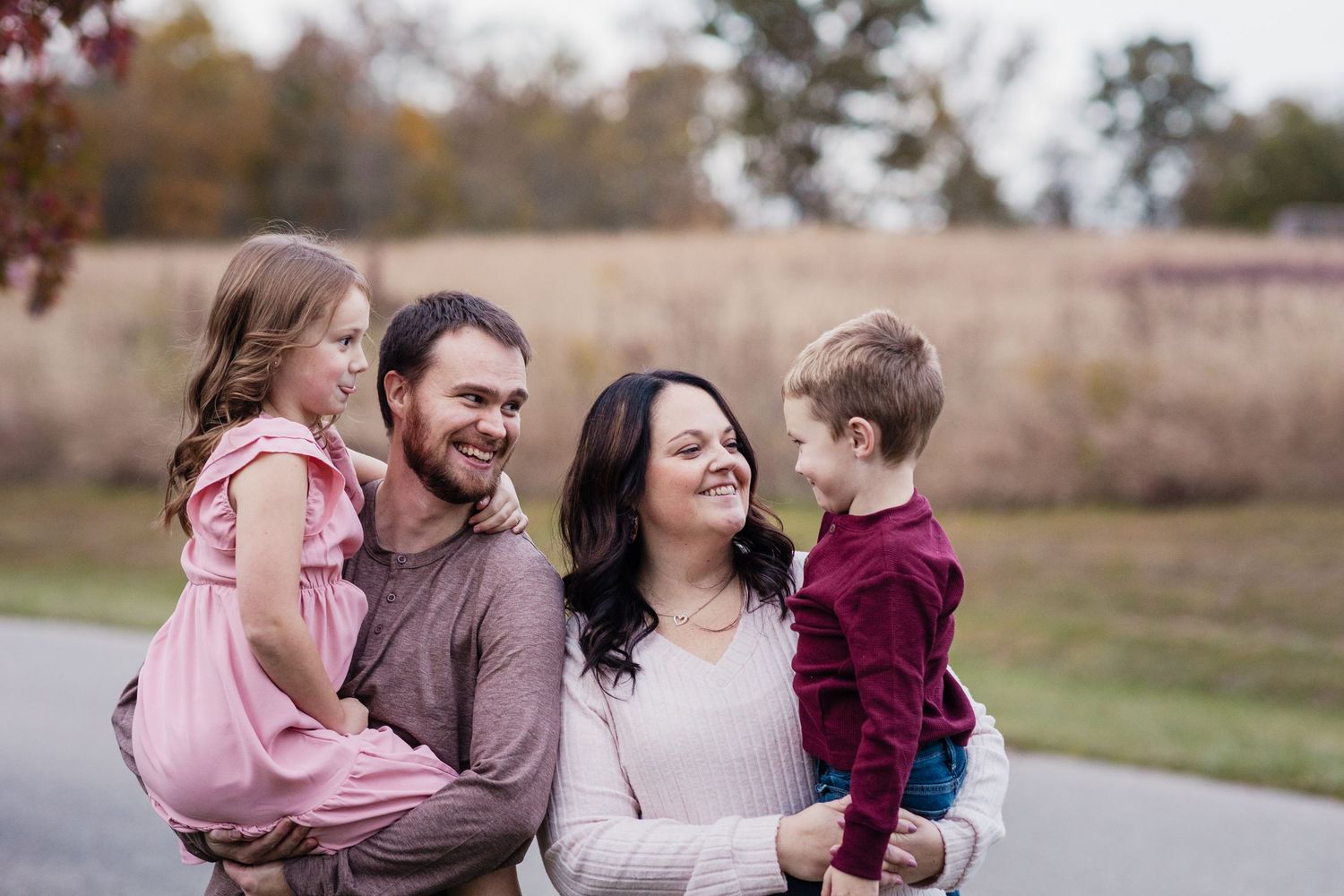Parents holding young daughter and son during outdoor fall family portrait.
