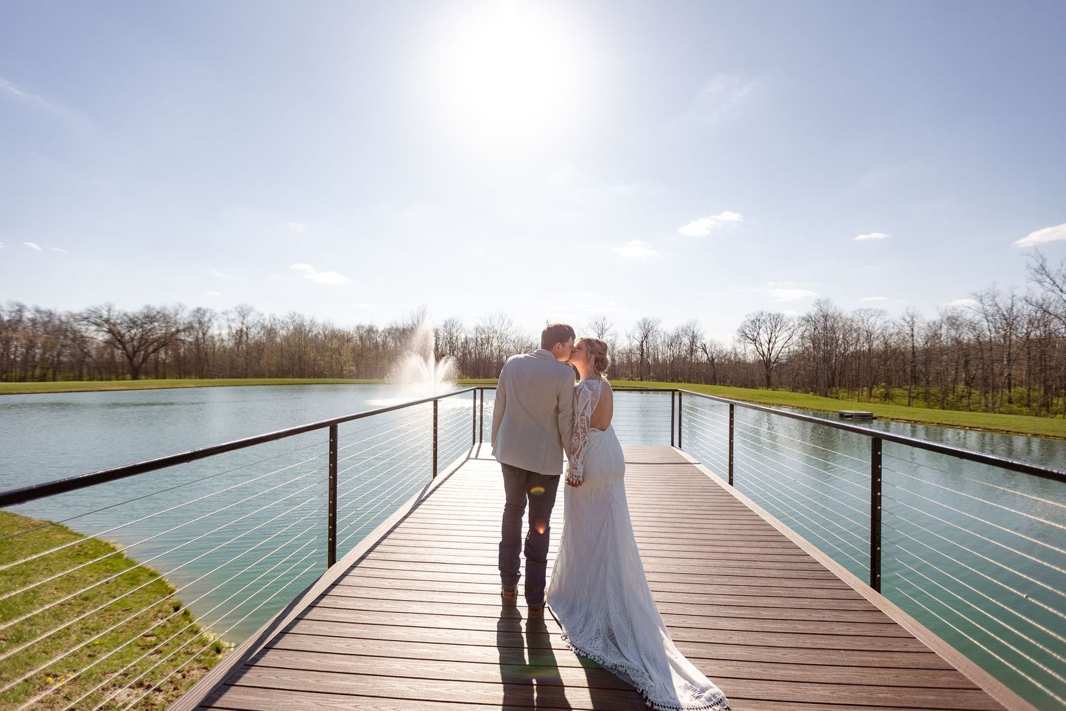 Bride and groom share a romantic moment on a wooden bridge overlooking a serene pond on their wedding day at Hanover Reserve.